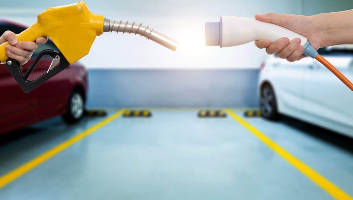 Human hands holding electric plug and gasoline nozzle